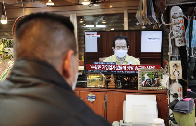 정부가 현행 사회적 거리두기 단계를 설 연휴가 끝날 때까지 2주 더 연장하겠다고 밝힌 31일 서울의 광장시장에서 한 상인이 TV로 거리두기 연장 발표를 시청하고 있다.