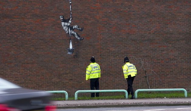 교도소 담장에서 내려오는 수감자를 처다보는 영국 경찰의 모습