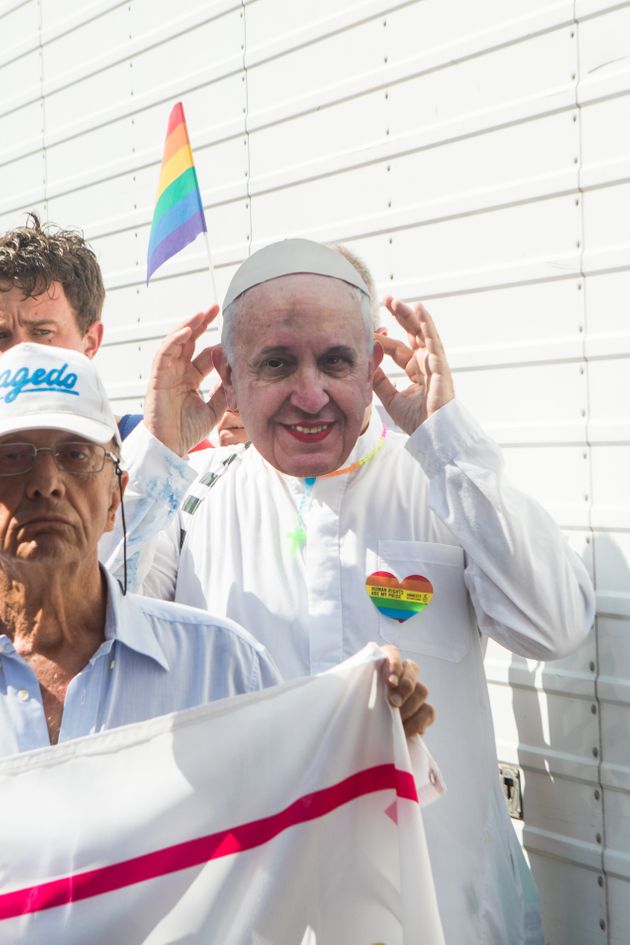 2019년 밀라노 퍼레이드 당시 한 성소수자가 교황 얼굴을 새긴 마스크를 쓰고 행진하는 모습.