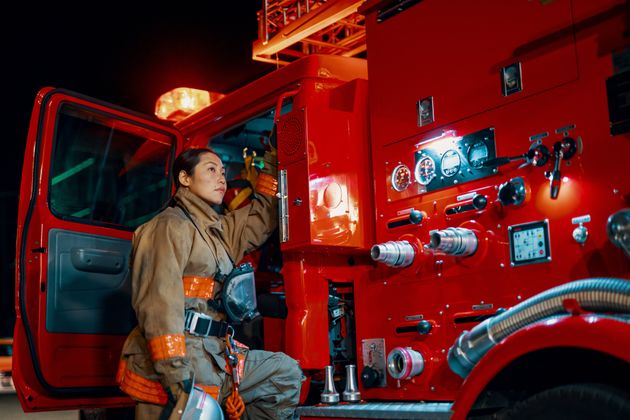 [자료사진] 여성 소방관이 소방차 옆에 서 있다.