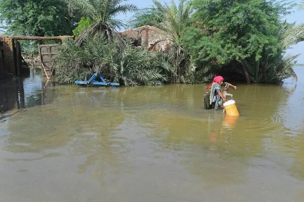 홍수 피해를 입은 한 여성이 침수 지역에서 식수를 채우고 있다. 출처: 게티 이미지 