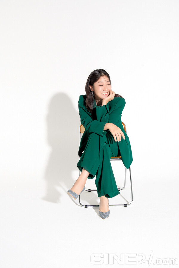 라미란이 녹색 의상을 입고 의자에 앉아 포즈를 취하고 있다. 출처: 씨네21