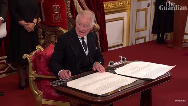 펜에 놓인 쟁반이 서명하는데 거슬리자 영국 국왕 찰스 3세가 얼굴을 한껏 찌푸리고 있다. (출처: 가디언 캡쳐)