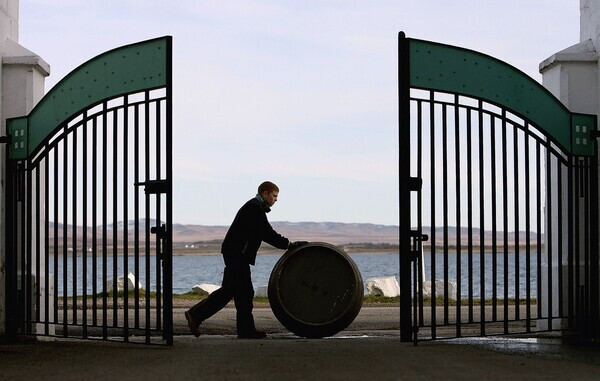 TARBERT, UNITED KINGDOM - MARCH 06:   A worker at Bruichladdich distillery is seen pushing a barrel on March 6, 2006, Bruchladdich in Islay, United Kingdom. Bruichladdich will use an ancient recipe to distil a whisky which will be at least 92% proof.  (Photo by Jeff J Mitchell/Getty Images)