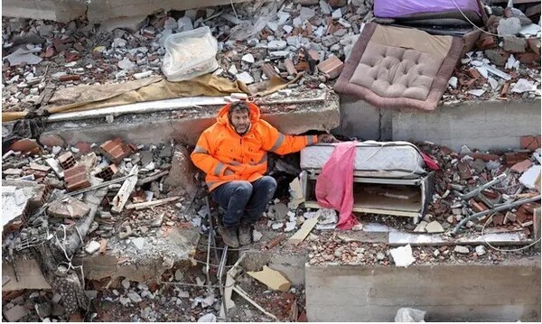 지난 7일 지진으로 폐허가 된 터키 카흐라만마라시의 아파트 폐허에 깔려있는 딸의 손을 잡고 앉아있는 메수트 한제르. ⓒAFP 연합뉴스