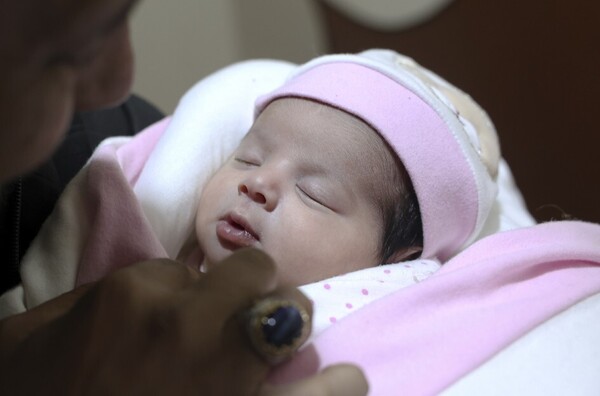 튀르키예를 강타한 대지진으로 무너진 시리아 알레포주 진데리스의 건물속에서 탯줄이 달린 채 구조된 여아 ‘아프라’가 20일(현지시각) 진데리스 고모집에서 고모부 칼릴 알사와디 품에 안겨 있다. 이 신생아는 그간 신의 계시, 기적을 뜻하는 ‘아야’(Aya)라는 이름으로 불리다가 이틀 전 병원에서 퇴원하고 고모집으로 입양되면서 숨진 어머니마의 이름 ‘아프라’를 물려받게 됐다. ⓒ진데리스/AP 연합뉴스