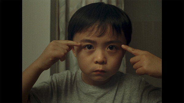 거울을 보며 자신의 눈 양 끝을 늘리는 동현. 친구들과 다른 자신의 얼굴에 의구심이 가득하다. ⓒ판씨네마