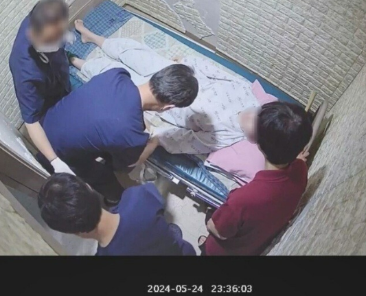 세 명의 남자 보호사들에 둘러싸여 손과 발, 가슴을 묶이는 5포인트 강박을 당하는 박아무개씨. ⓒCCTV