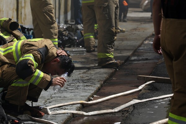 1일 오전 부산 금정구 회동동 한 화학물질 제조공장 2층 실험실에서 원인이 밝혀지지 않은 불이 난 가운데 진화작업에 나선 소방대원들이 잠깐 숨을 고르며 물로 더위를 식히고 있다. 소방당국은 대응 1단계를 발령하고 인원 98명과 장비를 동원해 화재 진화작업을 벌여 오전 7시 22분께 큰 불길을 잡았다. 2024.8.1/뉴스1