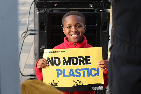 유엔 플라스틱 협약 제5차 정부 간 협상위원회 회의를 이틀 앞두고 23일 오후 부산 해운대구 올림픽공원 일대에서 열린 ‘1123 부산 플라스틱 행진’에 참석한 한 어린이가 손팻말을 들고 카메라를 바라보고 있다. ⓒ한겨레&nbsp;