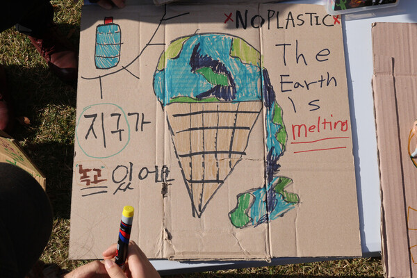 유엔 플라스틱 협약 제5차 정부 간 협상위원회 회의를 이틀 앞둔 23일 오후 부산 해운대구 올림픽공원 일대에서 열린 ‘1123 부산 플라스틱 행진’ 참가자가 손팻말을 만들고 있다. ⓒ한겨레