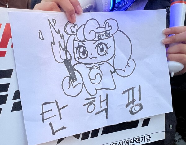 8일 오후 서울 여의도 국회의사당역 인근에서 촛불행동의 주최로 열린 촛불문화제에 한 시민이 캐릭터 '하츄핑'을 패러디한 그림을 들고 참가하고 있다. (2024.12.08) ⓒ뉴스1