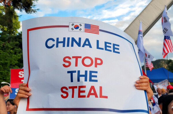 15일 서울대 정문 앞에서 열린 모스 탄 교수의 특별강연에 참석한 시민이 손팻말을 들고 있다.&nbsp;ⓒ뉴스1